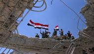 Syrian government forces' soldiers wave their national flags after taking back the city of Quneitra to the rebels, on July 19, 2018. Under pressure, rebels have agreed to hand over Quneitra and the buffer to government forces, an opposition negotiator and