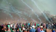 Palestinian protesters gather as tear gas canisters are launched by Israeli forces during a demonstration along the border between Israel and the Gaza strip, east of Gaza city on July 27, 2018. AFP / Mahmud Hams

