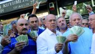 Businessmen holding U.S. dollars stand in front of a currency exchange office in response to the call of Turkish President Tayyip Erdogan on Turks to sell their dollar and euro savings to support the lira, in Ankara, Turkey August 14, 2018. Reuters/Umit B
