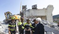 A handout photo made available by the Quirinal Press Office shows Italian President Sergio Mattarella (R) during his visit to the site of the highway-bridge-collapse disaster, before attending the State funeral of the victims, in Genoa on August 18, 2018.