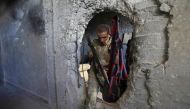 A Syrian rebel fighter who was displaced from Ghouta in the Damascus province earlier this year steps out through a hole in a damaged building in a rebel-held neighbourhood on the western outskirts of Aleppo in northern Syria on September 10, 2018.   AFP 