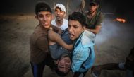 Protesters carry a Palestinian shot and wounded by Israeli troops on the 25th Friday of 