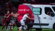 Flamengo football players Everton Ribeiro (L), Piris da Motta (C) and Brazil's Vasco da Gama player Andrey (R) and other teammates from both squads push the ambulance carrying Vasco da Gama's injured player Bruno Silva after it's engine failed to start on