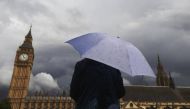 A woman looks towards dark clouds over the Houses of Parliament in central London, August 11, 2014. (Reuters/Luke MacGregor) 