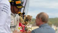 Russian President Vladimir Putin congratulates winner Mercedes' British driver Lewis Hamilton during the podium ceremony for the Formula One Russian Grand Prix at the Sochi Autodrom circuit in Sochi on September 30, 2018. / AFP / SPUTNIK / Mikhail KLIMENT