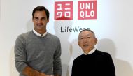 Switzerland's tennis player Roger Federer (L) shakes hands with Tadashi Yanai, founder and president of Fast Retailing, known as the UNIQLO brand, during the photo session of a press conference at the Fast Retailing headquarters in Tokyo on October 2, 201