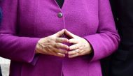 German Chancellor Angela Merkel holds her hands in her typical 
