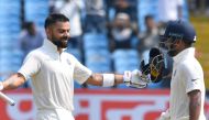 Indian cricket captain Virat Kohli celebrates after reaching his century (100 runs) as teammate Rishabh Pant looks on during the second day's play of the first Test cricket match between India and West Indies at the Saurashtra Cricket Association stadium 