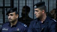 The accused look on behind police officers during their trail for staging an attack on December 2016 on a Crusader castle in Kerak, at the State Security Court, in Amman, Jordan November 13, 2018. REUTERS/Muhammad Hamed
