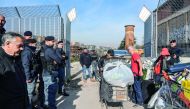 Italian Carabinieri policemen (L ad R) supervise Italian homeless citizens (C) carrying their belongings in shopping carts during the eviction of a makeshift migrants' camp known as 
