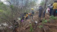 In this photograph taken with a mobile phone, Zimbabwe Rescue Services members look and search through the debris of a crashed light aircraft at Ngundu in Masvingo on November 23, 2018.   AFP / Bekithemba Dube
