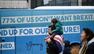 A man wearing a UK flag stands by a bus during a protest against Brexit outside the EU Headquarters in Brussels on November 25, 2018, in Brussels, as occurs a special meeting of the European Council to endorse the draft Brexit withdrawal agreement and to 
