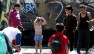 A child washes himself next to a watering hole in the refugees camp at the Greek-FYR of Macedonia border near the village of Idomeni on 23 May, 2016. AFP /Sakis Mitrolidis