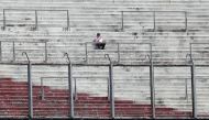 A supporter of River Plate sits on an empty stand at the Monumental stadium in Buenos Aires, after the all-Argentine Copa Libertadores second leg final match against Boca Juniors was postponed on November 25, 2018.   AFP / ALEJANDRO PAGNI