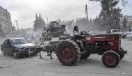 A Turkish-backed Syrian Arab fighter tows a looted vehicle with a tractor after seizing control of the northwestern Syrian city of Afrin from the Kurdish People's Protection Units (YPG) on March 18, 2018. AFP / BULENT KILIC