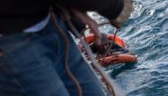 A crew member from the Dutch-flagged Sea-Watch 3 rescue vessel throws buoys and a rope to rescue a migrant back on board, after he dived on January 4, 2019 from the vessel in the cold Mediterranean off Malta's coast, in a attempt to reach the shore by swi