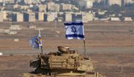 An Israeli flag flutters above the wreckage of an Israeli tank sitting on a hill in the Israeli-occupied sector of the Golan Heights on October 18, 2017. AFP/Jalaa Marey