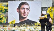 FILE PHOTO: People look at yellow flowers displayed in front of the portrait of Argentinian forward Emiliano Sala at the Beauvoir stadium in Nantes, on February 8, 2019.  AFP / LOIC VENANCE