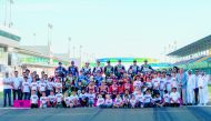 MotoGP riders, FIM and QMMF officials pose for a photograph with young Qatar Motor Academy riders at Losail International Circuit, yesterday.