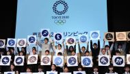 Japan's 4x100 metre relay Rio 2016 silver medallist Shota Iizuka (top row 6th L), national karate team member Kiyo Shimizu (top row 6th L) and elementary school students display sports pictograms for the Tokyo 2020 Olympic Games during an unveiling ceremo