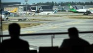 Two persons look from the viewing gallery of Changi International Airport different aircrafts including a SilkAir Boeing 737 MAX aircraft (background C) parked on the airport tarmac in Singapore on March 12, 2019. AFP / Roslan RAHMAN