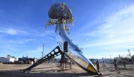 People visit an installation sculpture of a crashed plane by artist Randy Polumbo, on the first day of the Bombay Beach Biennale, March 22 2019 in Bombay Beach, California.  AFP / Robyn Beck