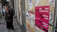 A woman walks past a poster in the Koukaki area in Athens, which in 2016 was named Airbnb's fifth fastest growing neighbourhood globally with an 800-percent jump in home-sharing. AFP/Louisa Gouliamaki