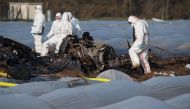 Forensic experts and police inspect the burnt out remains of a small plane lie on an asparagus field after it crashed the day before in Erzhausen near Darmstadt, Germany on April 1, 2019.  AFP / Boris Roessler
