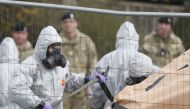 British military personnel wearing protective coveralls work to remove a vehicle connected to the March 4 nerve agent attack in Salisbury from a residential street in Gillingham on March 14, 2018. AFP/Adrian Dennis