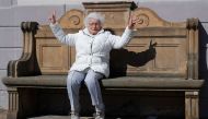 Lisel Heise, a 100-year-old former teacher, sits on a stone bench from 1921 and flashes victory signs in front of the townhall in Kirchheimbolanden, Germany, April 11, 2019. REUTERS/Kai Pfaffenbach