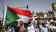 Sudanese protestors wave national flags and shout slogans as people continue to protest outside the army complex in the capital Khartoum on April 17, 2019.  AFP / OZAN KOSE