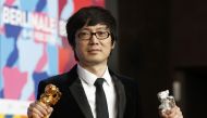 Chinese director Diao Yinan poses with the Golden Bear for Best Film and the Silver Bear for Best Actor trophies during a press conference following the awarding ceremony of the 64th Berlinale Film Festival on February 15, 2014.  AFP / David Gannon 