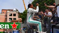 First placed Mercedes' British driver Lewis Hamilton (L) almost bends over after jumping at a fence to greet fans as he celebrates winning the pole position after the qualifying session at the Monaco street circuit on May 25, 2019 in Monaco, ahead of the 