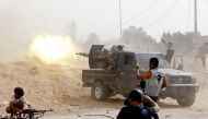A fighter loyal to the Libyan internationally-recognised Government of National Accord (GNA) fires a heavy machine gun as a press photographer take pictures of the scene during clashes against forces loyal to strongman Khalifa Haftar, on May 25, 2019, in 