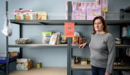 Rosi Bianchi, in charge of the food aid distribution, poses in front of shelves of food in Campione d'Italia, a tiny Italian enclave on the shores of Switzerland's Lake Lugano, on May 7, 2019. AFP / Fabrice Coffrini

