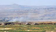 Smoke billows above buildings in the town of Kafr Nabuda in the north of the Syrian Hama province during reported air strikes by Syrian regime forces on May 26, 2018.   AFP / George OURFALIAN