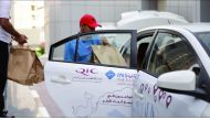 Volunteers from Qatar Insurance distributing Iftar meals by roadside. 