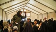 Fightres from the Syrian Democratic Forces (SDF) check the identities of displaced people before allowing them to board a bus waiting outside the Al-Hol camp in Al-Hasakeh governorate in northeastern Syria, on June 3, 2019, as Kurdish authorities started 