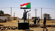 A Sudanese protester holds a national flag as he stands on a barricade along a street, demanding that the country's Transitional Military Council hand over power to civilians, in Khartoum, Sudan June 5, 2019. Reuters