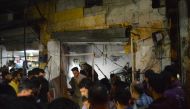People gather around the wreckage of shops after a terror attack with a bomb-laden vehicle carried out in Azez district of Aleppo, Syria on June 02, 2019. According to reports at least 14 civilians were killed after the attack. (Saher el Hacci/Anadolu Age