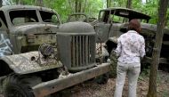 A woman looks at wreckage of trucks in the ghost city of Pripyat during a tour in the Chernobyl exclusion zone on June 7, 2019.  AFP / Genya Savilov 