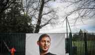 Flowers candles are left with front page of French a daily newspaper reading The disappearance of a warrior next to a portrait of Emiliano Sala in front of the entrance of the FC Nantes (AFP/Loic Venance) 