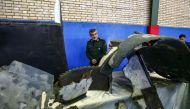 General Amir Ali Hajizadeh (C), Iran's Head of the Revolutionary Guard's aerospace division, looks at the debris from a downed US drone reportedly recovered within Iran's territorial waters and put on display by the Revolutionary Guard in the capital Tehr
