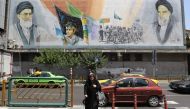 An Iranian woman walks past a mural painting depicting the late founder of the Islamic Revolution Ayatollah Ruhollah Khomeini (R) and Iran's supreme leader Ayatollah Ali Khamenei in the Iranian capital Tehran on June 25, 2019.  AFP / Atta Kenare 