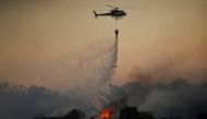 A helicopter drops water over a wildfire near the city of Toledo, Spain June 28, 2019. REUTERS/Juan Medina