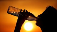 A woman drinks water during sunset, as a heatwave hits France, in Cagnicourt near Cambrai, France, June 25, 2019. Reuters/Pascal Rossignol