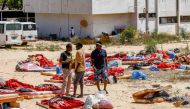  Migrants stand and walk outside at a detention centre used by the Libyan Government of National Accord (GNA) in the capital Tripoli's southern suburb of Tajoura on July 3, 2019, following an air strike on a nearby building that left dozens killed the pre