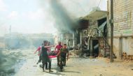 Civil defence crew members carry an injured person away from the scene after airstrikes by Assad Regime hit the de-escalation zone of Maar Shurin village in Idlib, Syria on July 16, 2019. At least 9 civilians were killed and 14 injured. (Izeddin Idilbi/An