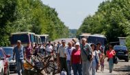 People stand near a checkpoint before crossing the contact line between pro-Russian rebels and Ukrainian troops in Mayorsk, Ukraine July 3, 2019.  Reuters/Gleb Garanich