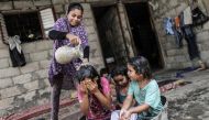 A Palestinian children take a bath in a slum on the outskirts of the Khan Yunis refugee camp, in the southern Gaza Strip on July 17, 2019, during a heat wave. AFP / Mahmud Hams
 